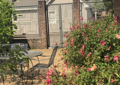 Gate leading into a garden with wrought iron table and chairs.